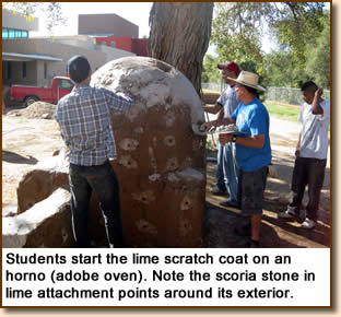 Students start the lime scratch coat on an horno (adobe oven). Note the scoria stone in lime attachment points around its exterior.